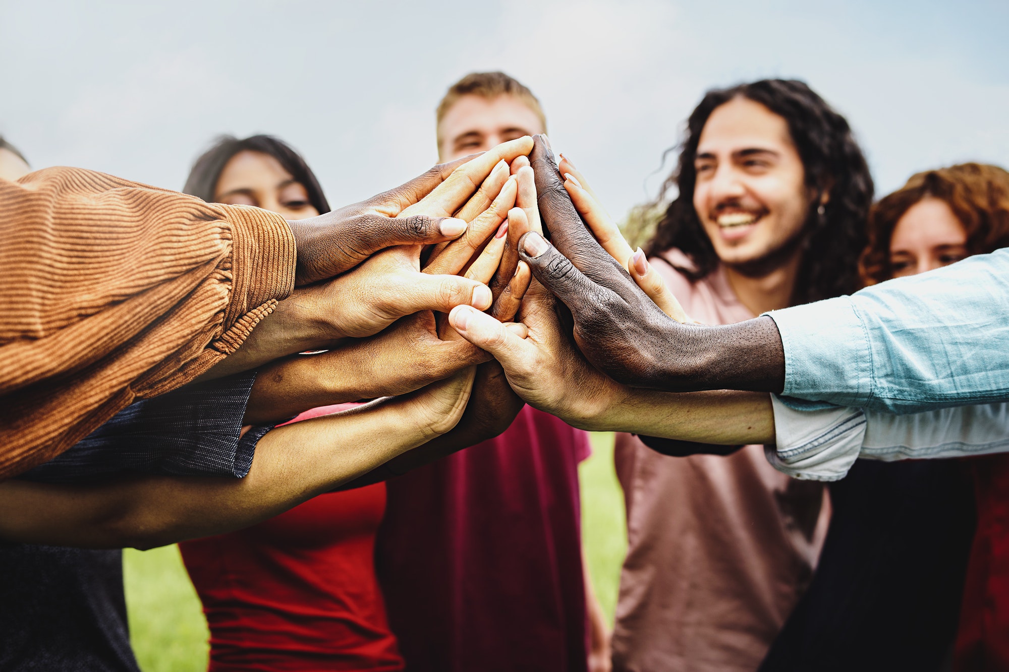 Joyful group of multi-ethnic community of happy people having fun joining hands in the park