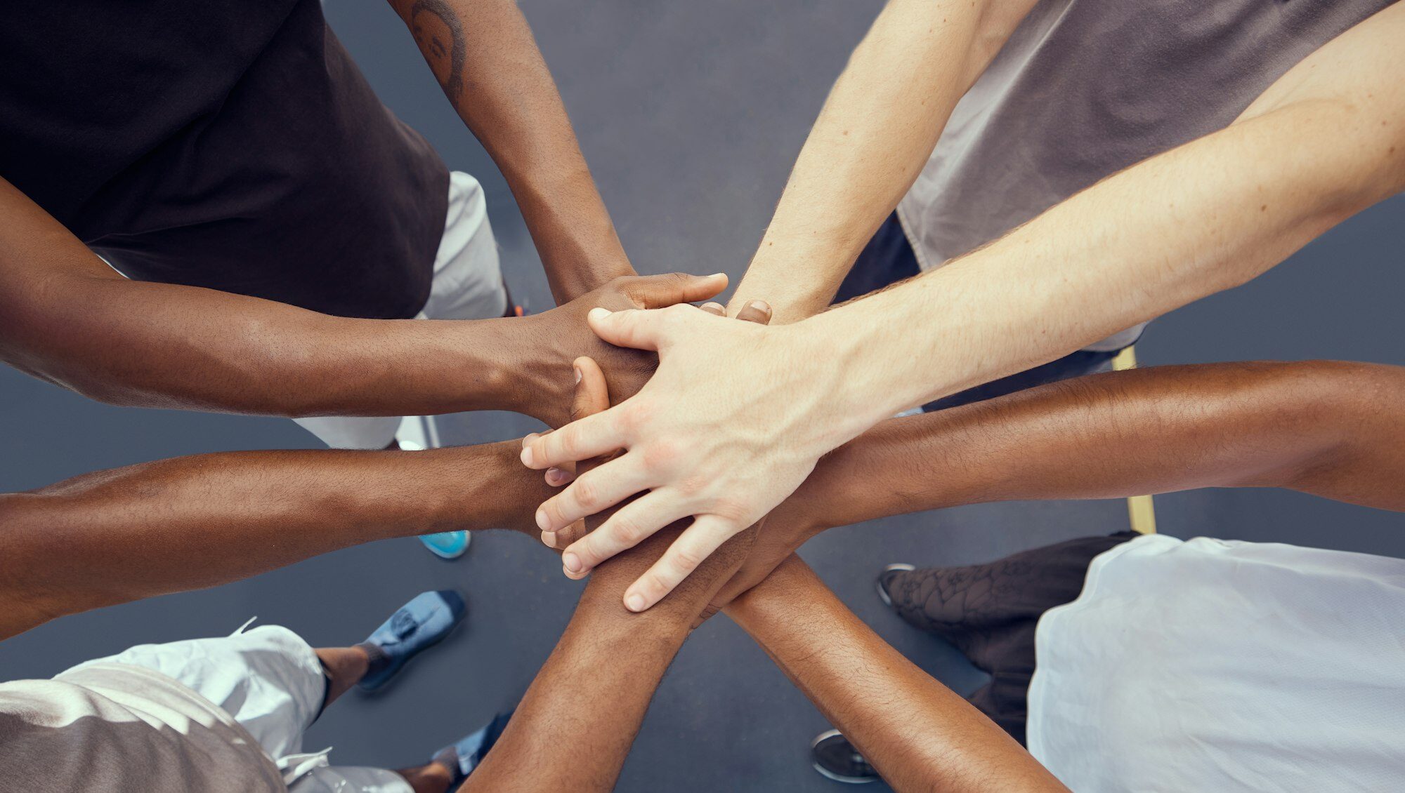 Teamwork, solidarity and diversity sports people hands stacked together from above. Athlete group o